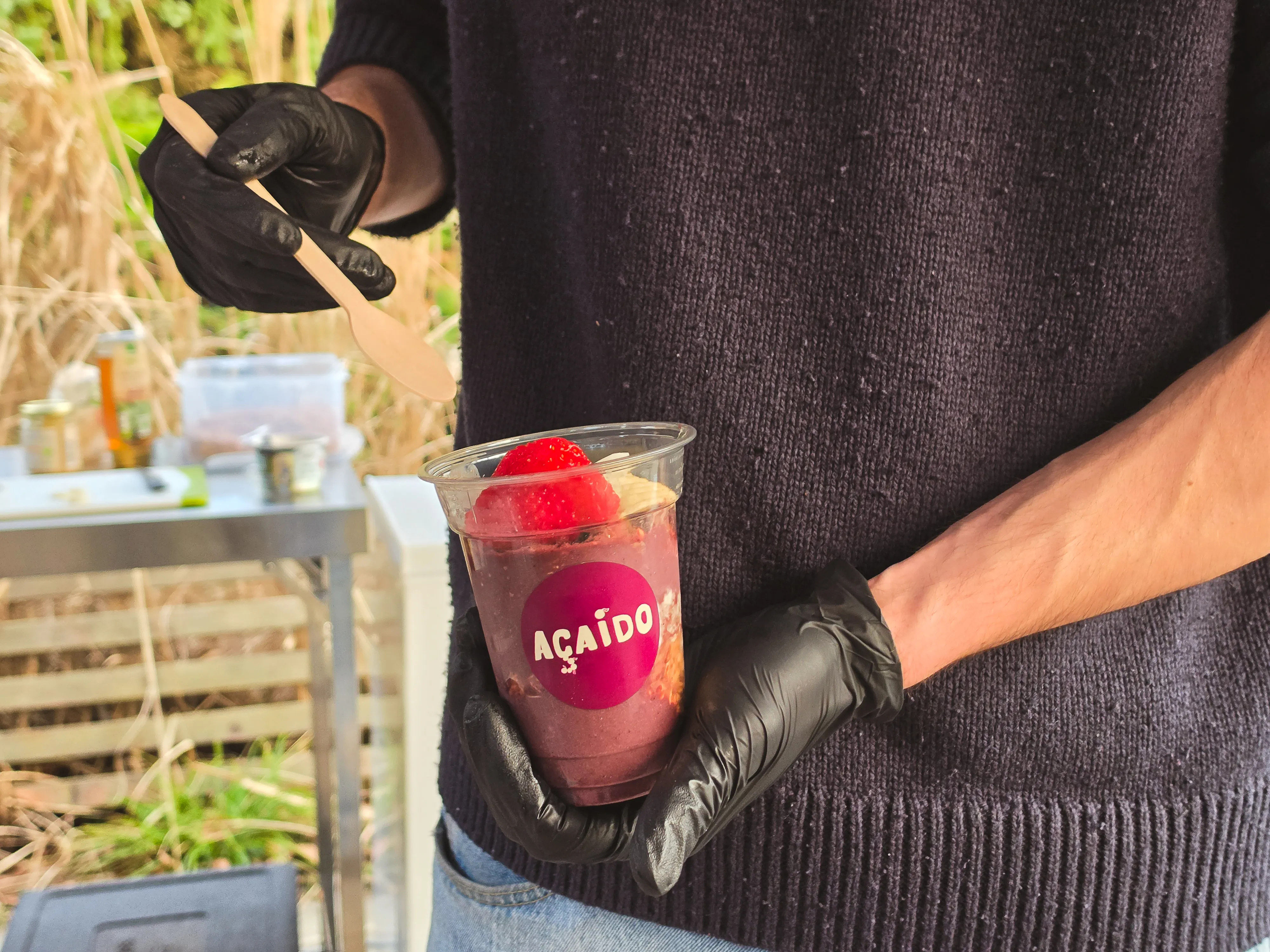 Servierfertige gesunde Açaí Bowl in einem Becher auf dem Isemarkt Hamburg in der Hand eines Mitarbeiters